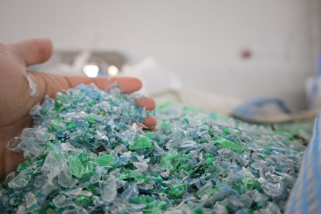 Geri dönüştürülmüş PET plastik pulları tutan bir el.