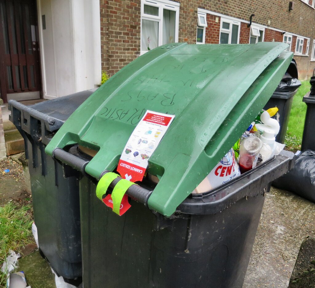 Plastik poşetlere karşı talimatlarla "kirlenmiş" olarak işaretlenmiş taşan bir geri dönüşüm kutusu.